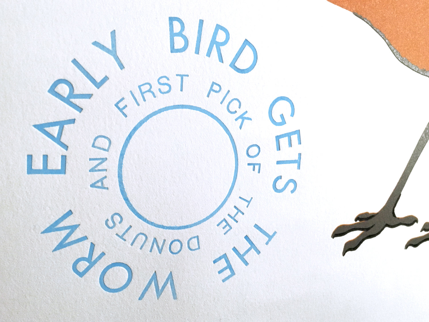 detail of the text that reads: EARLY BIRD GETS THE WORM AND FIRST PICK OF THE DONUTS" the detail also shows the impression the text made in to the soft paper it was printed on